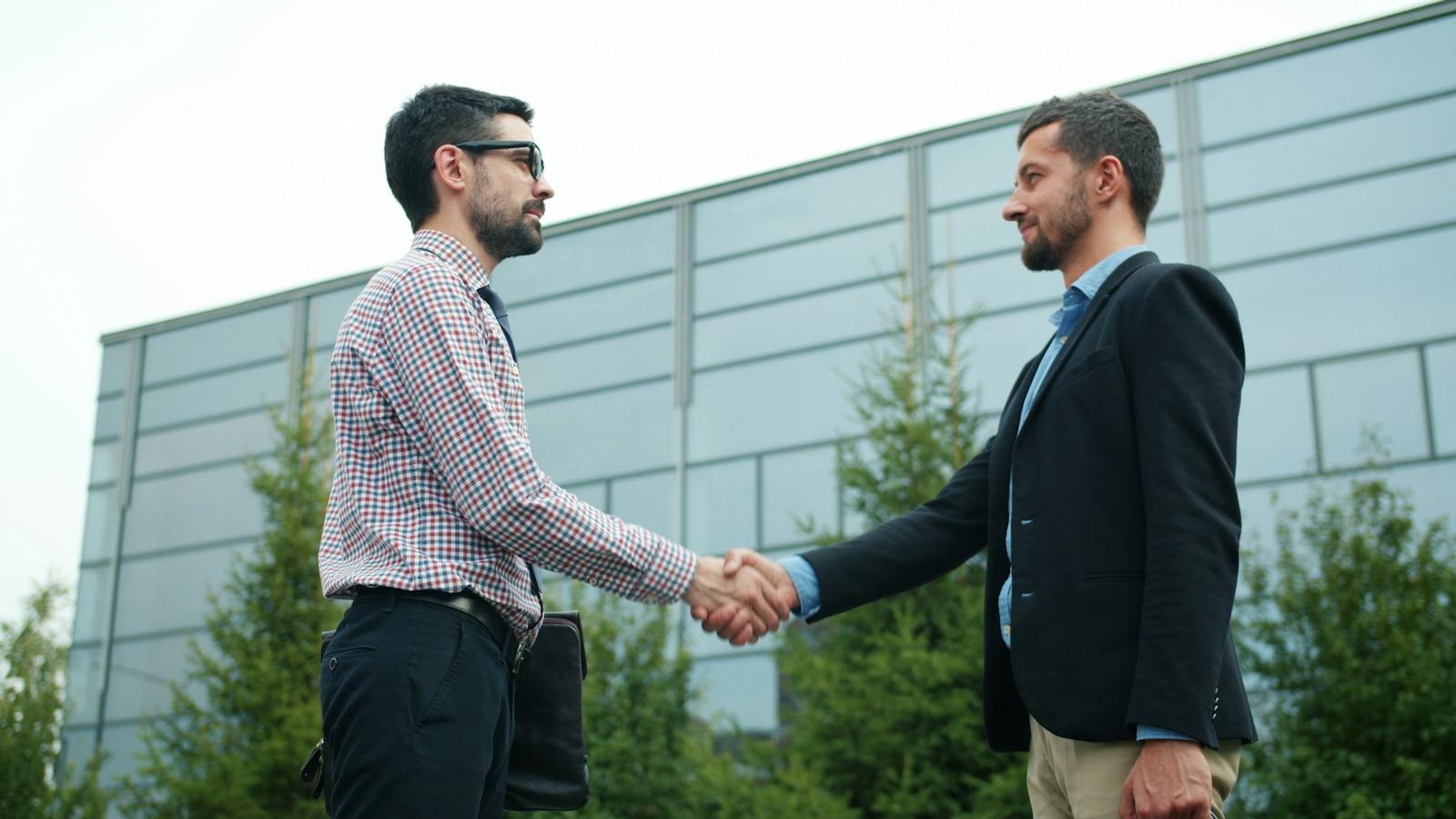 Podanie ruky dvoch obchodných partnerov pred budovou